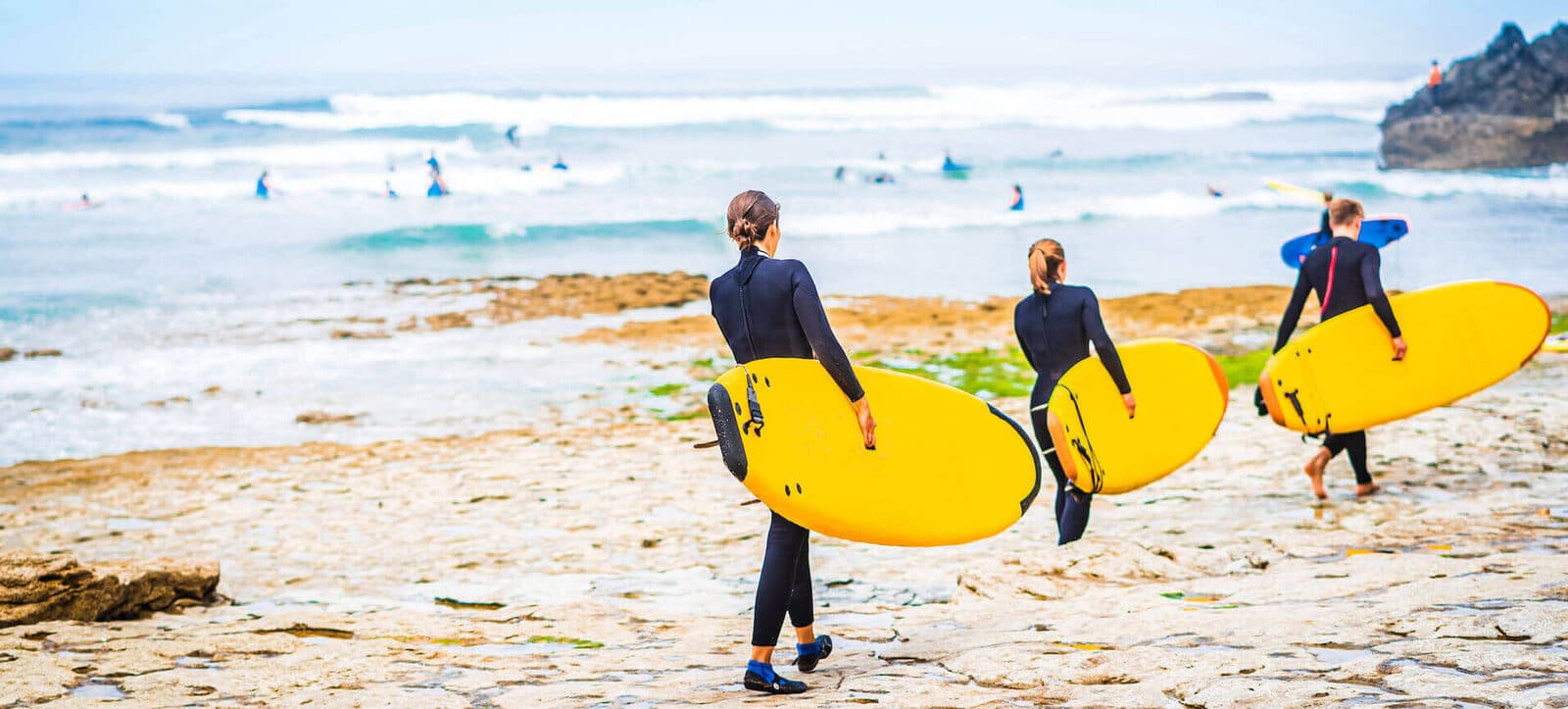 Alunos a caminhar para o mar com pranchas de surf